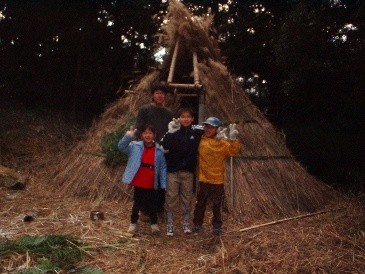 縦穴式住居の前で、リーダーと子どもたちで記念撮影